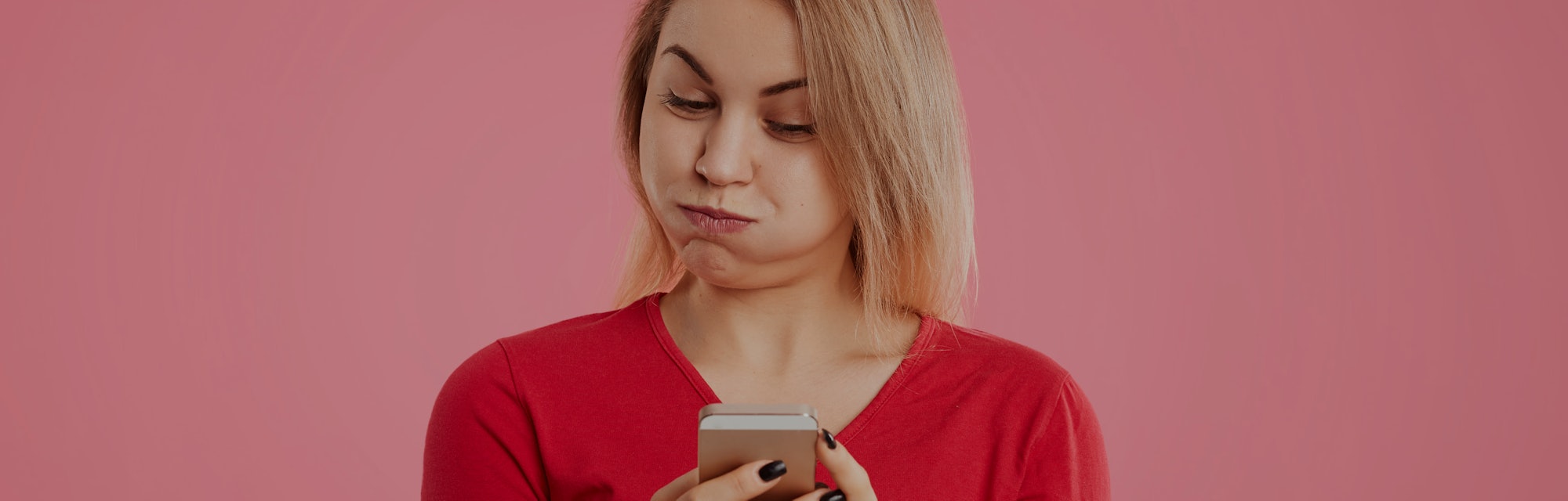 A woman looks frustrated and confused at her phone.