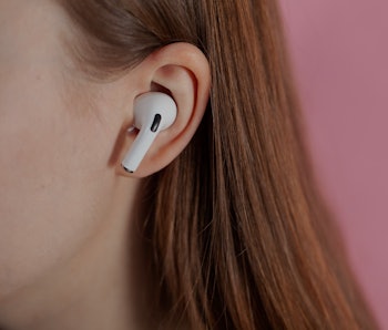 girl uses wireless white headphones on a pink background. Air Pods Pro. with Wireless Charging Case....