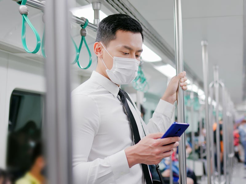 Asian business man with surgical mask face protection use a smartphone and keep social distancing t...
