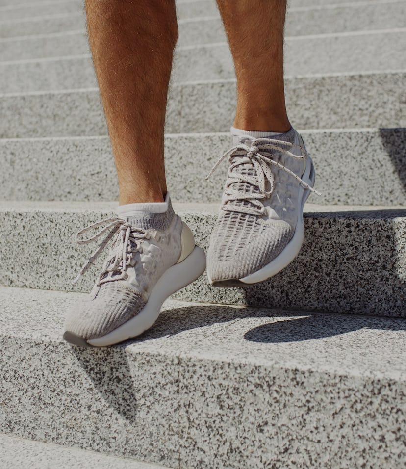Young man exercising outside. Picture of man's feet in sneakers walking down steps outside duing sun...