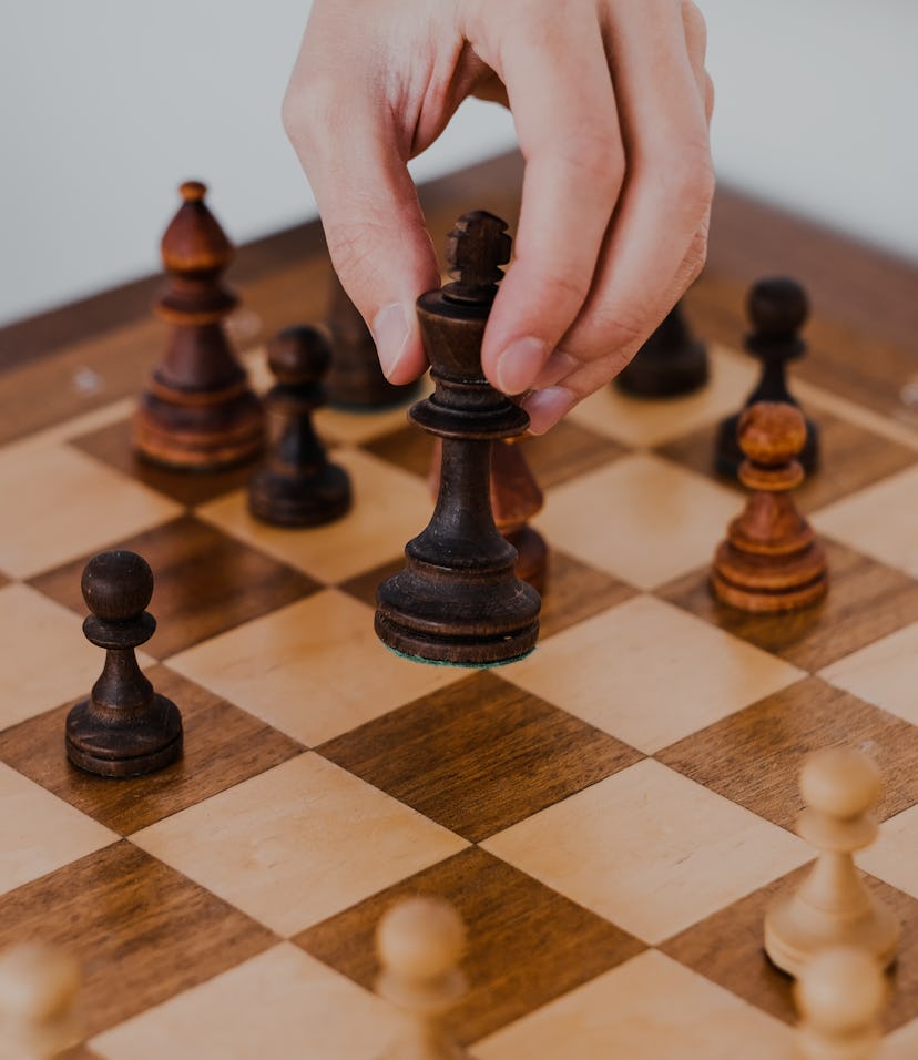 man holds a chess piece with his hand. Chess board. game of chess on a white background. chess tourn...