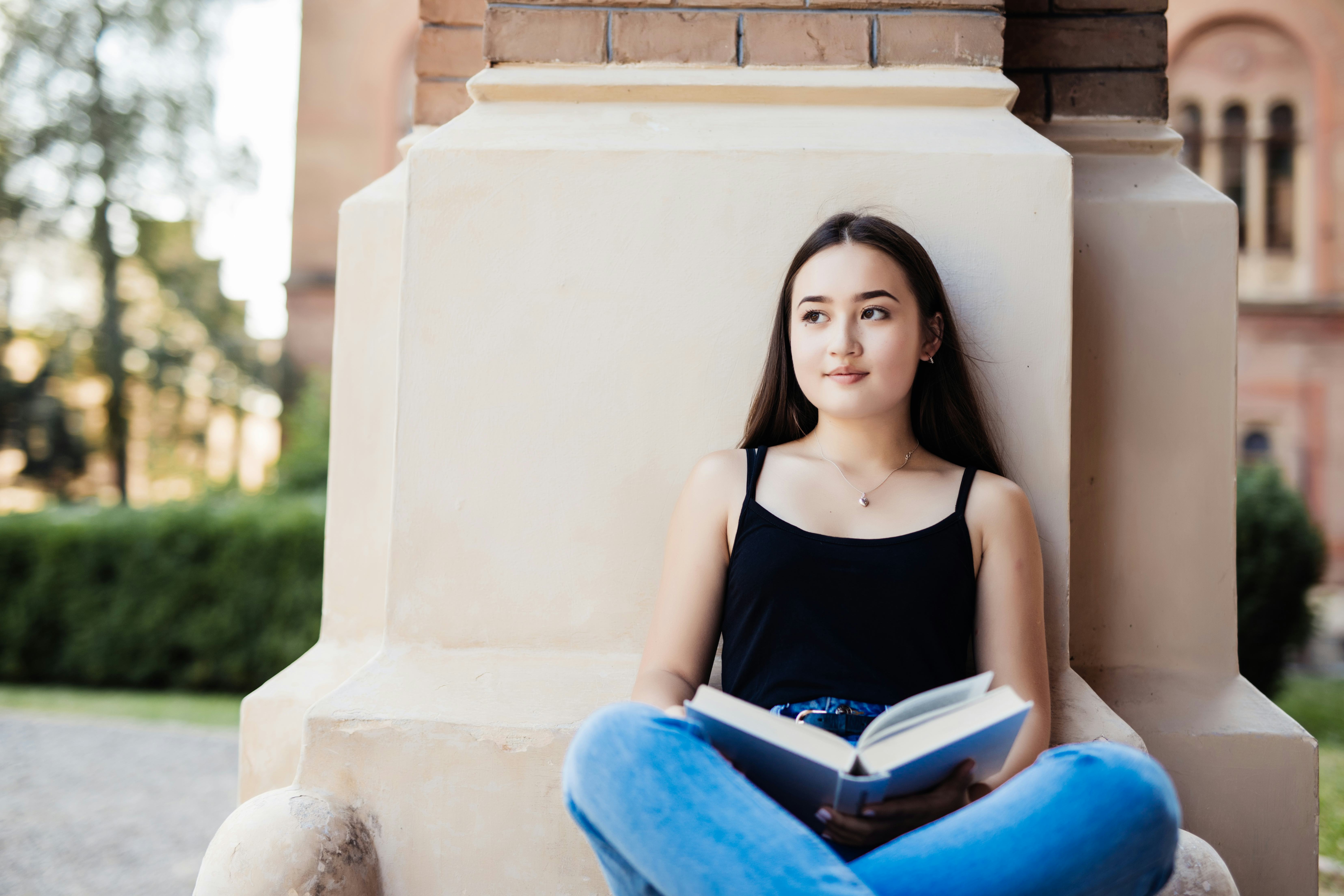 Young woman sits holding a book and smiling
