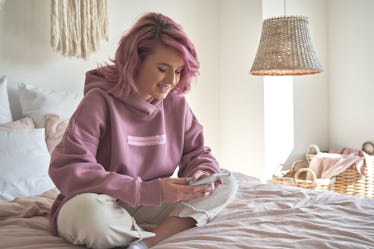 A woman sitting in trendy pink room looking at #BamaRush 2022 dorm inspiration on TikTok.