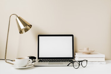 Blank screen laptop. Home office desk table workspace with coffee, lamp, glasses, notebook on beige ...