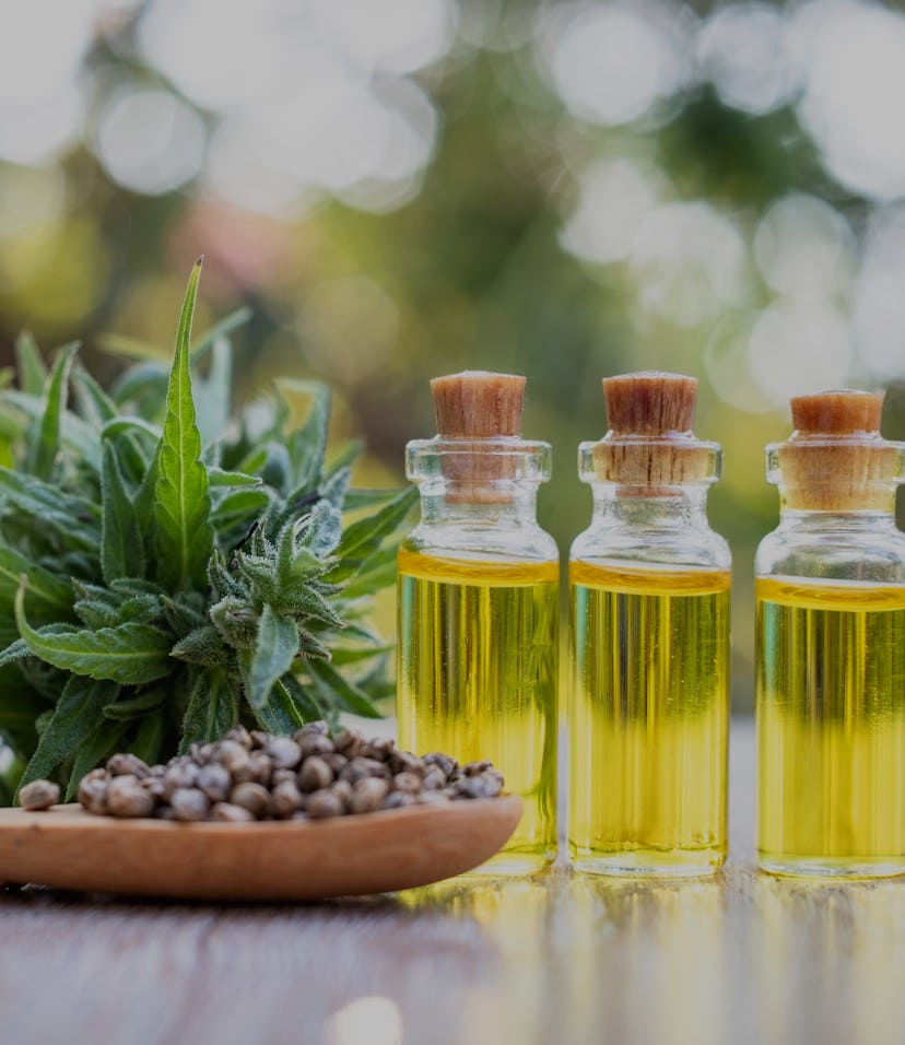 CBD oil alongside leaves and a wooden spoon.