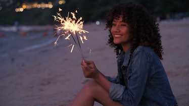 A beautiful woman playing fireworks on the beach.