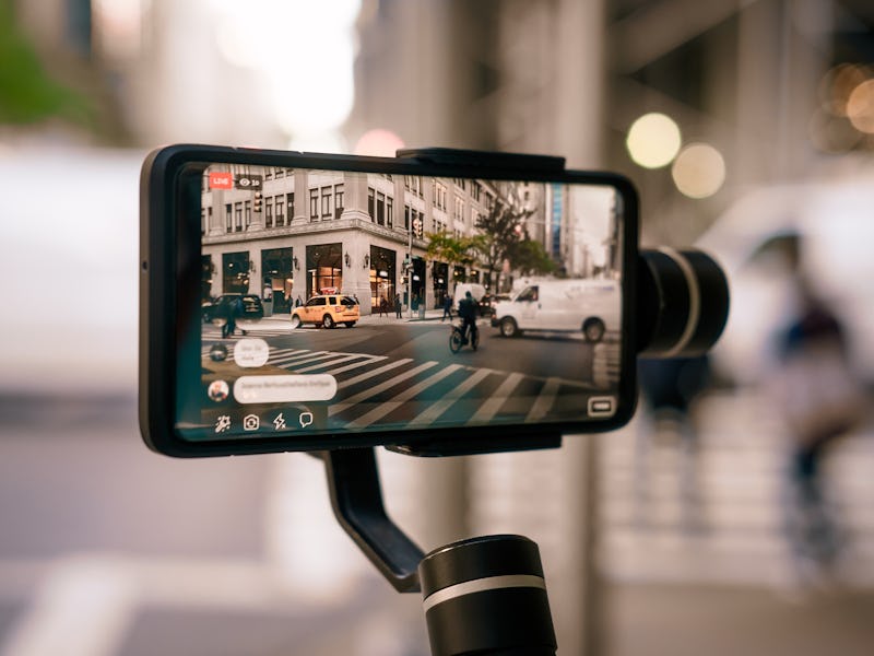 Man using phone with stabilizer and taking pictures and live video in New York city. Vlog, video blo...