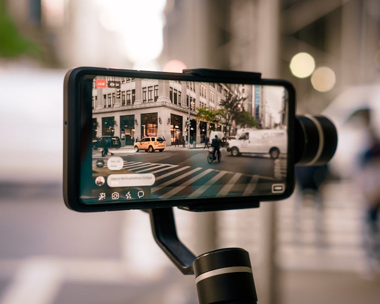 Man using phone with stabilizer and taking pictures and live video in New York city. Vlog, video blo...