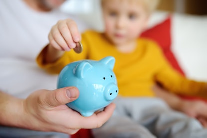 Father and child putting coin into piggy bank. Education of children in financial literacy. Money, c...