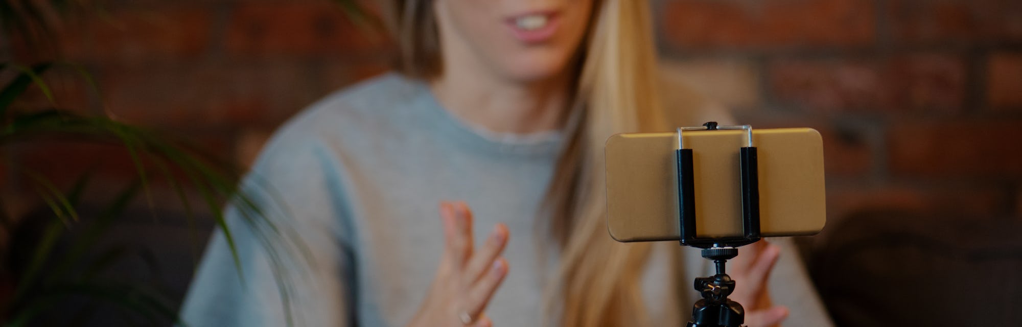 Woman recording video blog at home using mobile phone.