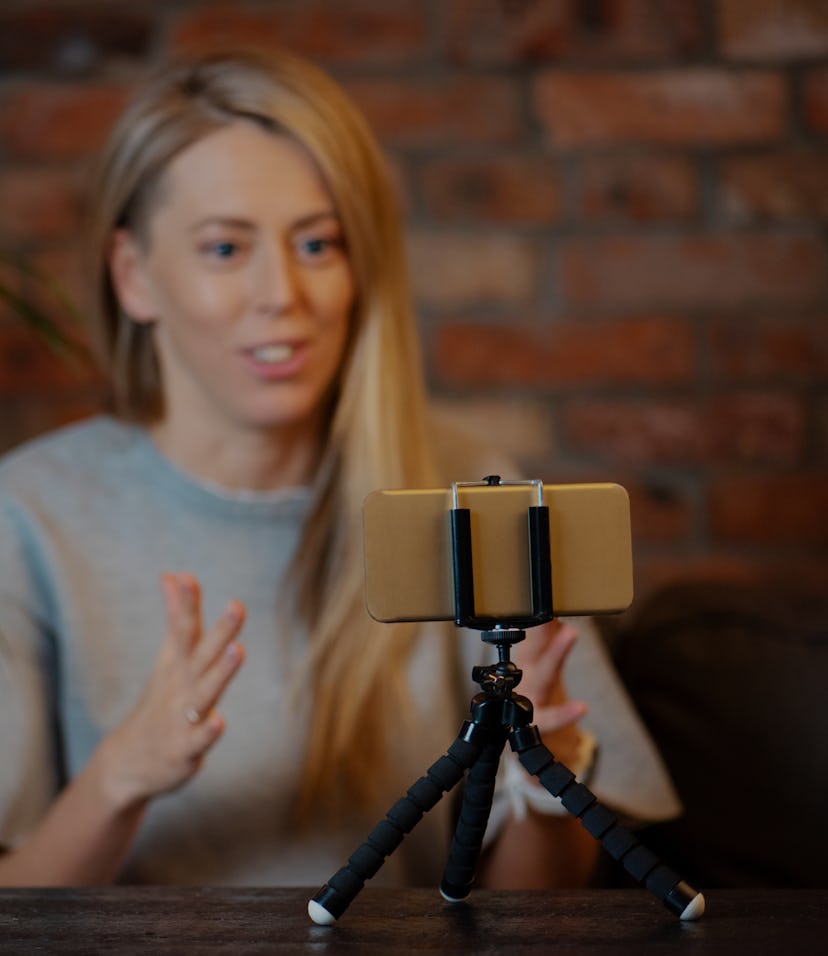 Woman recording video blog at home using mobile phone.