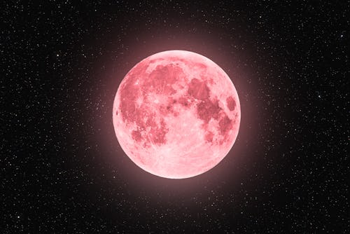 A full moon is glowing in the starry night sky with a pink hue. The spiritual meaning of April's ful...