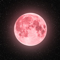 A full moon is glowing in the starry night sky with a pink hue. The spiritual meaning of April's ful...