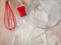 Overhead cooking background. White flour and red silicone tools on wooden cutting board. Baking proc...