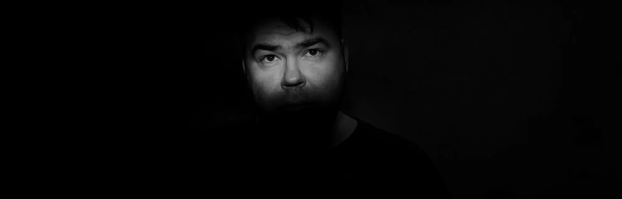 Portrait of a man with a green eye for horror or halloween. a narrow strip of light on the face, in the eyes. nightmare in dusk