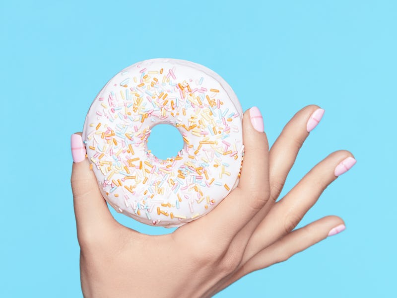 Manicure. Hand With Pastel Nails Holding Donut. Close Up Of Female With Beauty White Manicure Holdin...