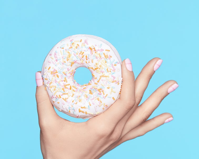 Manicure. Hand With Pastel Nails Holding Donut. Close Up Of Female With Beauty White Manicure Holdin...