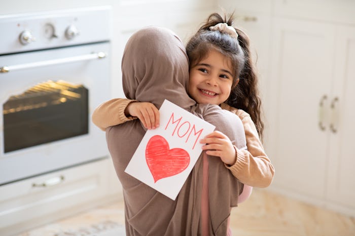 a happy little girl giving her mom a handmade Mother's Day card