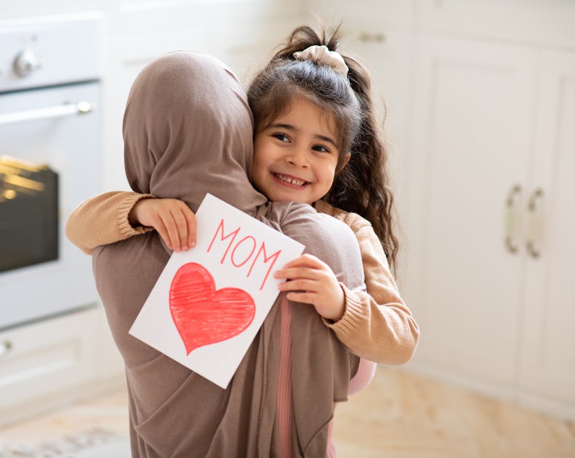 a happy little girl giving her mom a handmade Mother's Day card