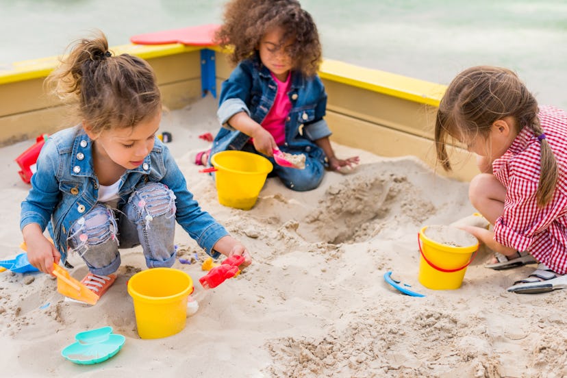 three girls playing in a sandbox