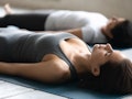 During yoga therapy session women lying in Shavasana Corpse Dead Body asana close up focus on Caucas...
