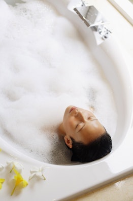 Woman in bathtub, eyes closed, high angle view