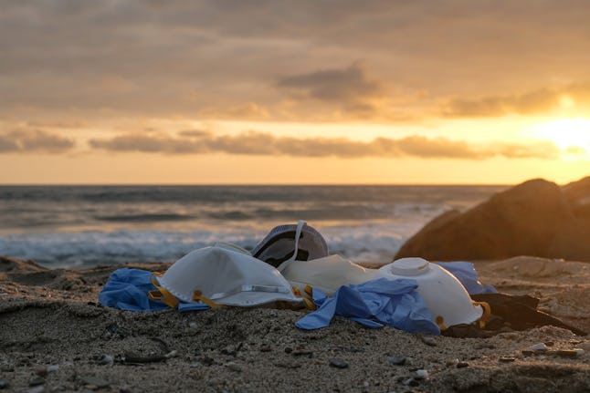 Medical waste,mask and plastic gloves garbage trash on sunset sea shore,coronavirus covid pollution disease