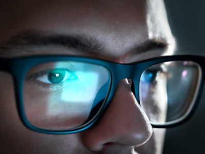 Computer screen light reflect from glasses. Close up of eyes. Business man, coder or programmer work...
