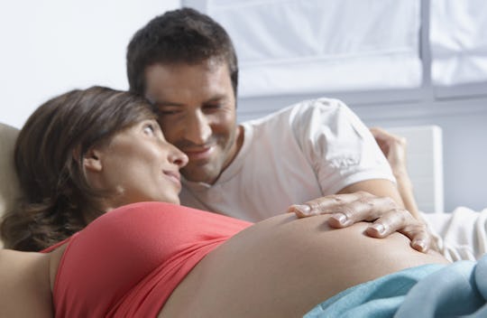 Man touching stomach of pregnant woman in bed at home