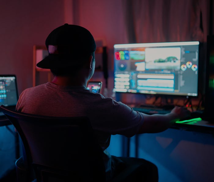 Blogger working editing video footage and looking at the monitor in-home office while working on pos...