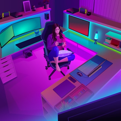 Staying at home during the pandemic playing video games. A girl sits on a gaming chair at a desk pla...