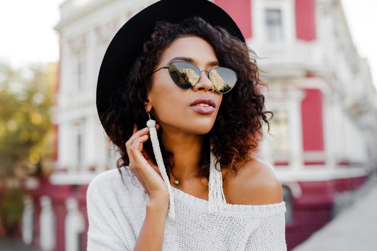 Close up portrait of fashionable black woman with stylish Afro hairs posing outdoor. Urban backgroun...