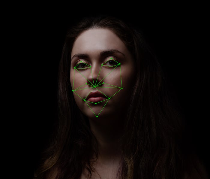 A young woman looks at the screen with a map of light green dots on her face. It is cast by a machin...