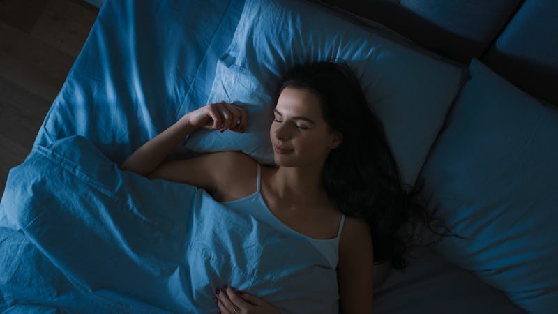 Woman lying in bed under sheets