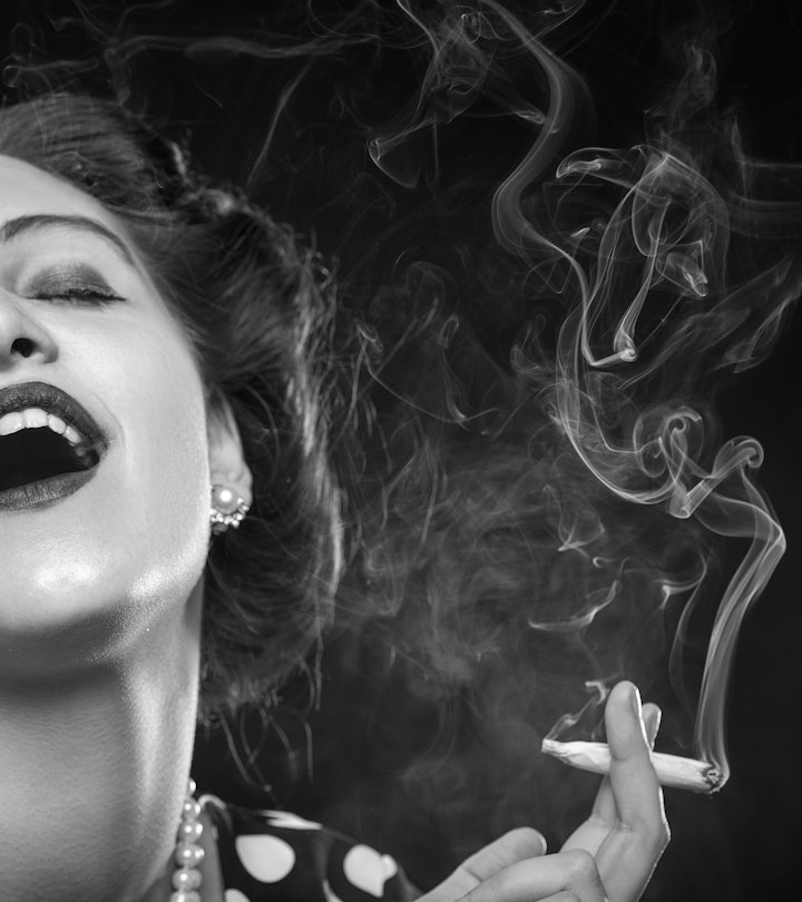 happy young woman smoking joint on black background, monochrome