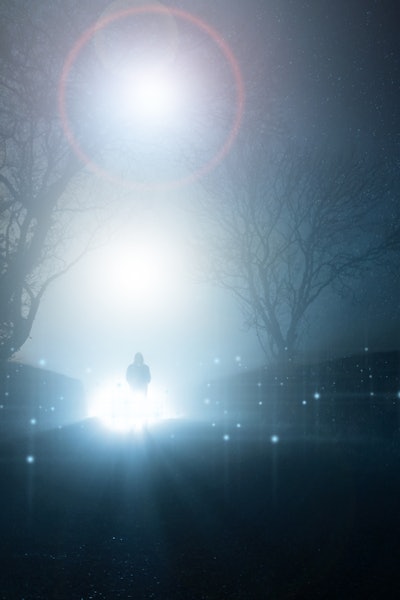 A supernatural, UFO concept of a scary, mysterious hooded figure, standing in front of a bright ligh...