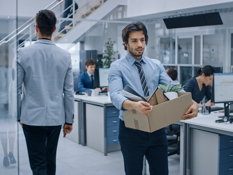 Sad Fired / Let Go Office Worker Packs His Belongings into Cardboard Box and Leaves Office. Workforc...