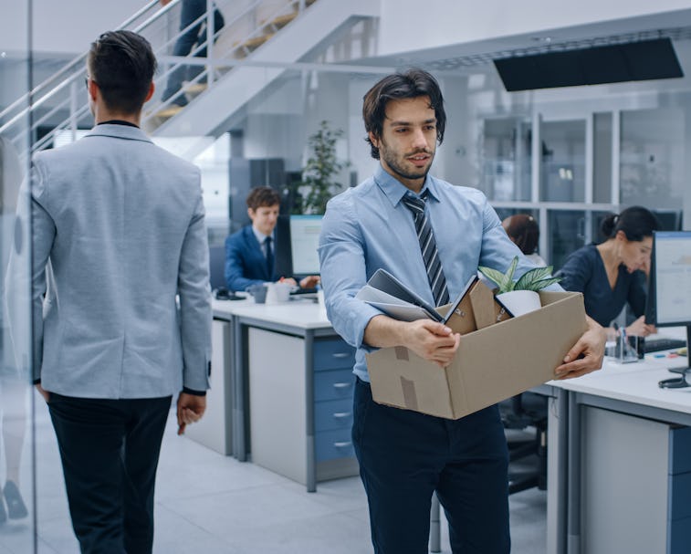 Sad Fired / Let Go Office Worker Packs His Belongings into Cardboard Box and Leaves Office. Workforc...