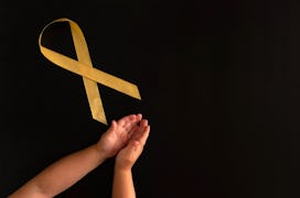children's hands next to the symbol of the fight against childhood cancer. go gold childhood cancer....
