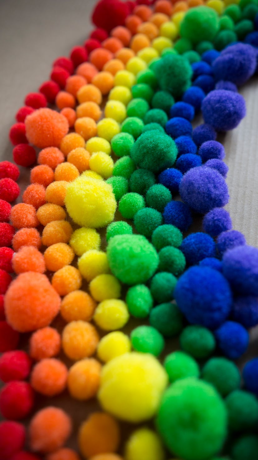 Happy, colorful rainbow pattern made of fluffy pom pom balls.