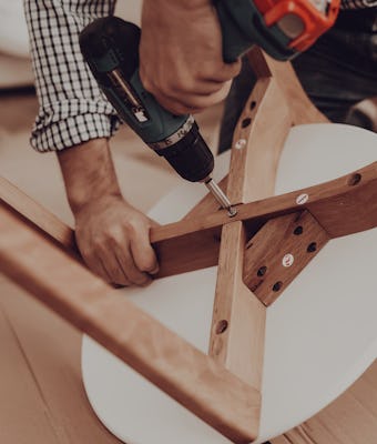 Assemble Furniture. Man Repairing Chair. Man Collects Chair. Furniture Assembler with Drill. Woman o...