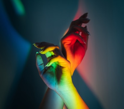 A pair of hands in rainbow lights to show the zodiac signs that will change most in 2022.