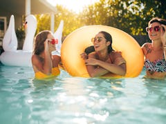 Happy young female friends in swimming pool with inflatable ring. Smiling women enjoying in a pool.