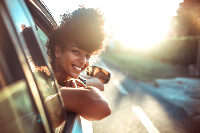 A woman is smiling as she sticks her head out of a car window. Sagittarius zodiac sign strengths inc...