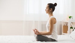 Morning Meditation. Woman Practicing Yoga On Bed After Waking Up, Side View, Free Space