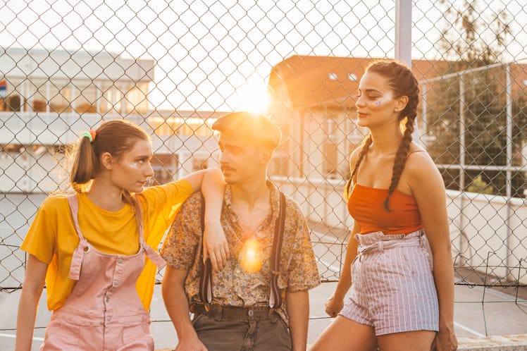 Teen boy sits between two teen girls, not sure which one to choose. Relationship concept