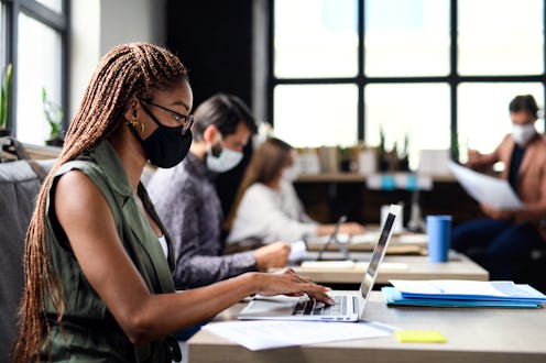 Business people with face masks indoors in office, back to work after coronavirus lockdown.