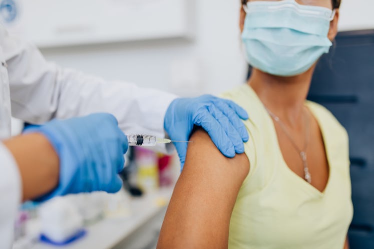 Female doctor or nurse giving shot or vaccine to a patient's shoulder. Vaccination and prevention ag...