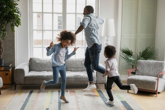 A dad and his two kids having a dance party in the living room