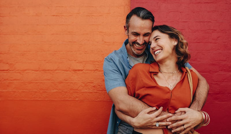 Beautiful couple in love embracing standing against a wall. Romantic couple together on multicolored...